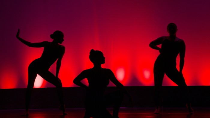 Drei tanzende Silhouetten vor rotem Hintergrund