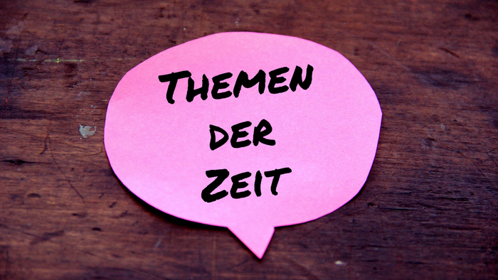Sprechblase mit der Aufschrift Themen der Zeit auf einer Tischplatte