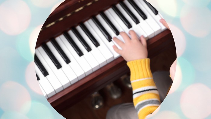 Zwei Kinderhände, die auf einer Klaviatur musizieren.