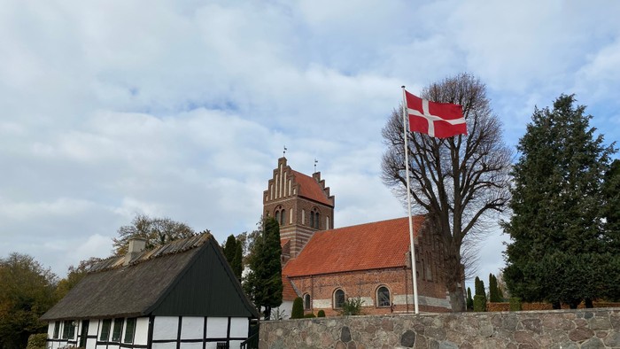 En dansk kirke med flag og hestestald.