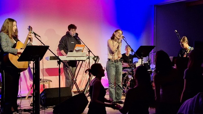 Eine Band spielt auf einer Bühne vor einem Publikum.
