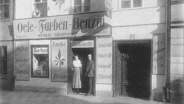 Historisches Foto: Vor dem Ladengeschäft 'Oele-Farben-Benzin' stehen eine Frau und ein Mann.