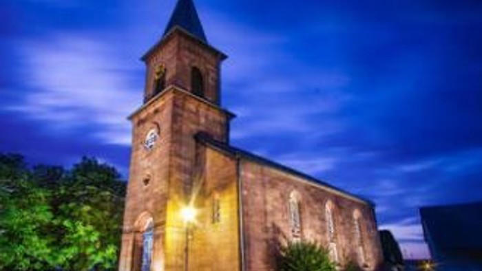 Eine Kirche mit einem Uhrturm, die nachts beleuchtet ist.