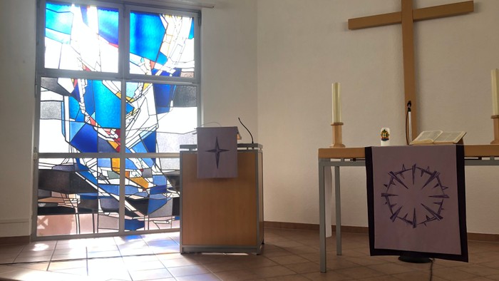 Kircheninneres mit Buntglasfenster, Kreuz und Lesepult