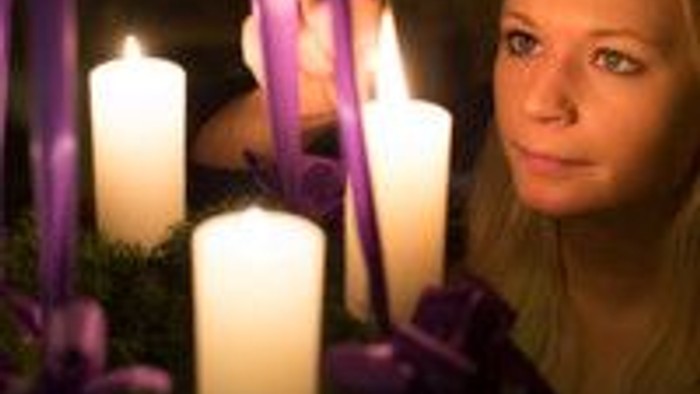 En kvinde med lysende lys og violette blomster.