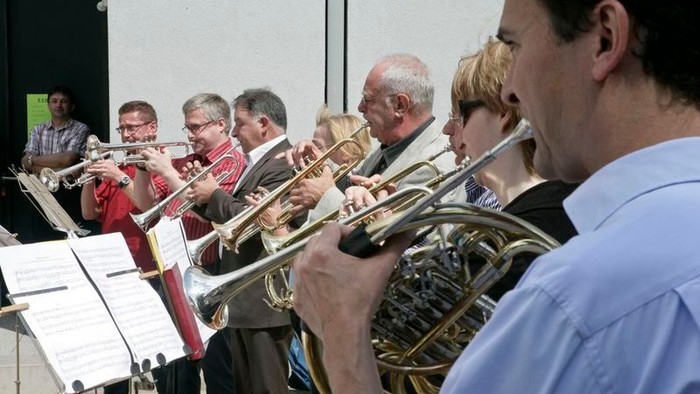 Eine Gruppe von Musiker:innen, die Blechblasinstrumente bei einem Open-Air-Konzert spielen.
