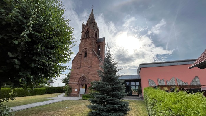 Kirche mit hohem Kirchturm und Weihnachtsbaum davor.