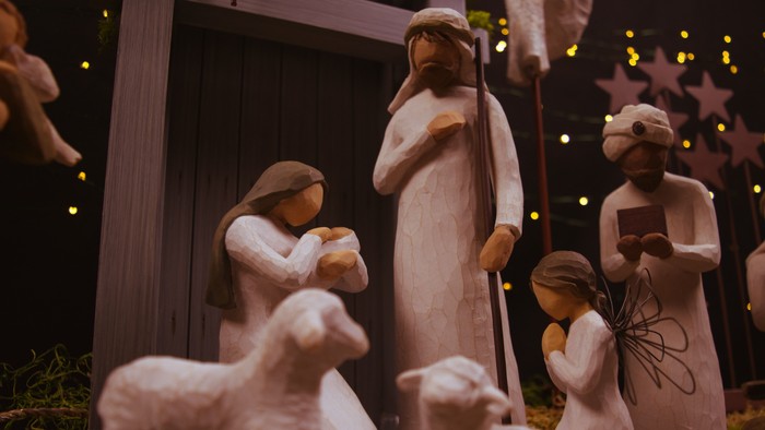En julekryddesættning med figurer og dyr foran en lille hytte.