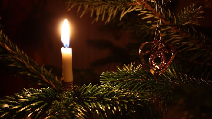 En lysende lyse på en julegren med et hjerteformet pynt.