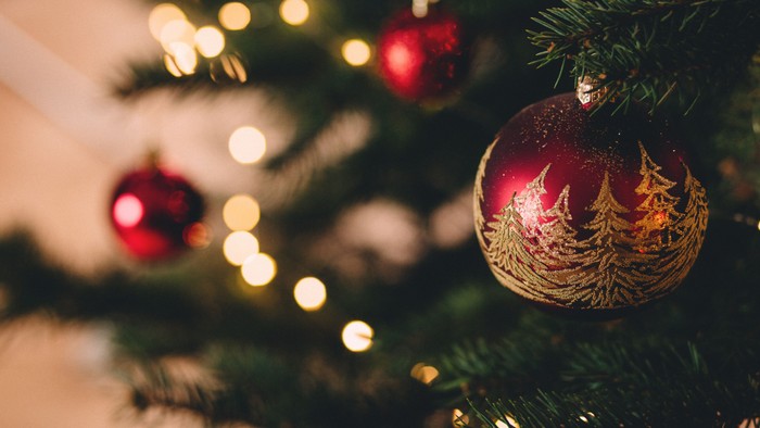 En juletree med røde glitrende pynt og lys.
