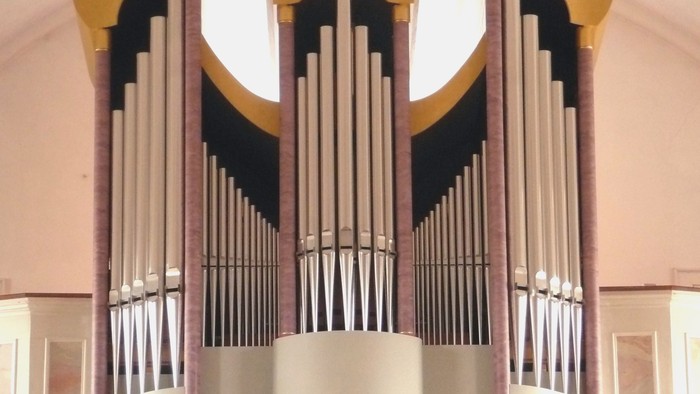 Elegante Pfeifenorgel mit goldenen Akzenten und mehreren Reihen polierter Pfeifen in einem prächtigen Ambiente.