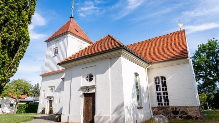 Weißes Kirchengebäude mit rotem Dach und Turm unter blauem Himmel