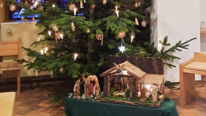 Weihnachtsbaum in der Kirche mit Krippe und Lichtern