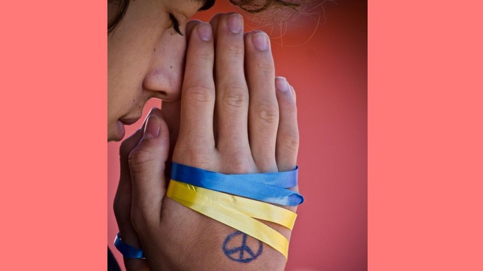 „Am Handgelenk der Person ist ein blau-gelbes Band gewickelt, und auf ihrem Arm ist ein Peace-Zeichen tätowiert.“