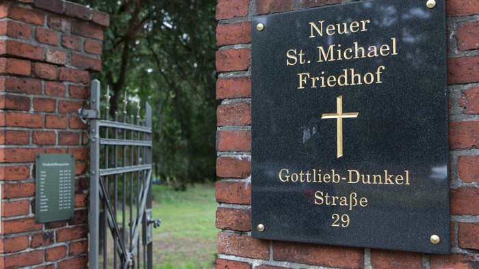 Plaque an Ziegelmauer mit Namen und Kreuz