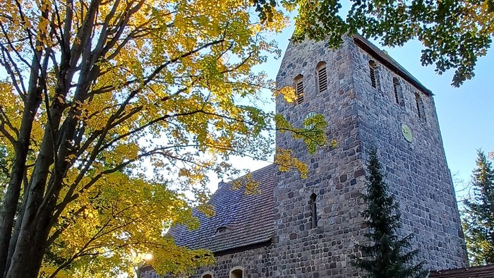 Dorfkirche Marienfelde umgeben von Bäumen mit Herbstlaub