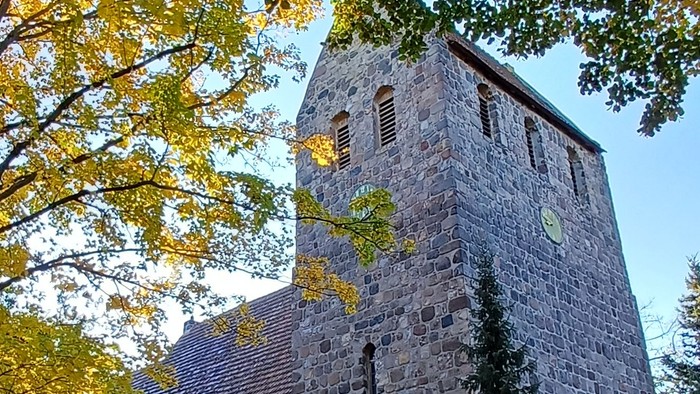 Dorfkirche Marienfelde umgeben von Bäumen mit Herbstlaub