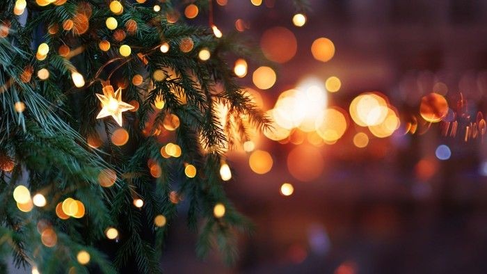 Et nærbillede af et juletræ pyntet med blinkende lys og en stjernepynt.