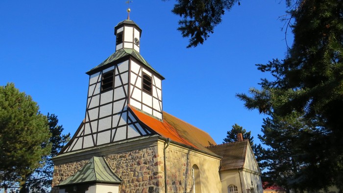 Das Bild zeigt eine historische Kirche mit einem markanten Turm und einem spitzen Dach.