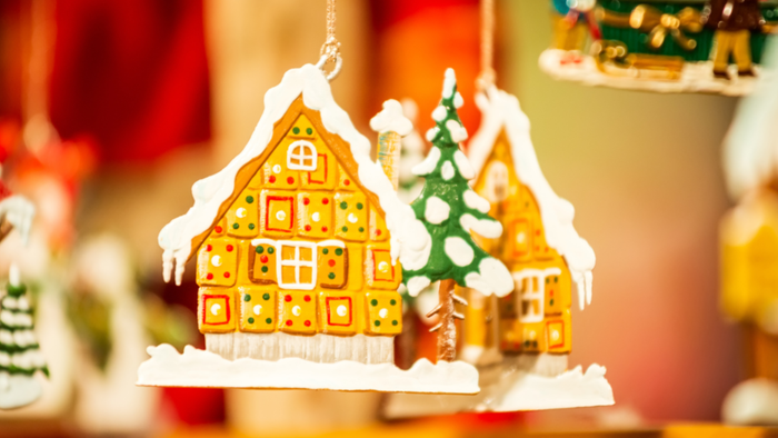 Dekorativer Lebkuchenhaus-Anhänger mit einem schneebedeckten Tannenbaum zwischen zwei Häusern.