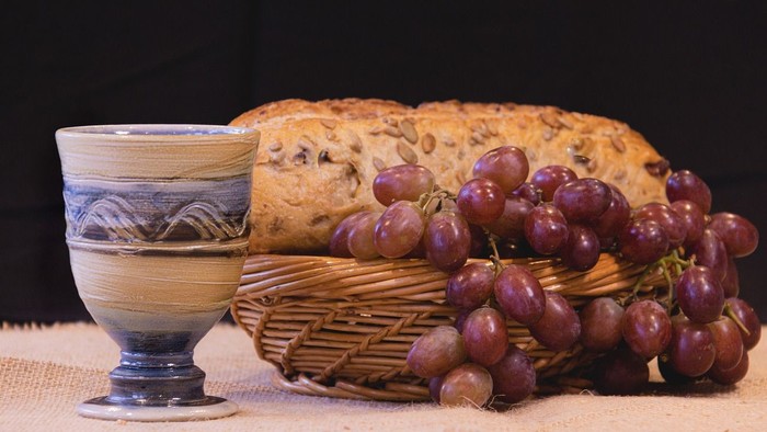Ein Korb mit Brot und Trauben neben einer Keramikschale.