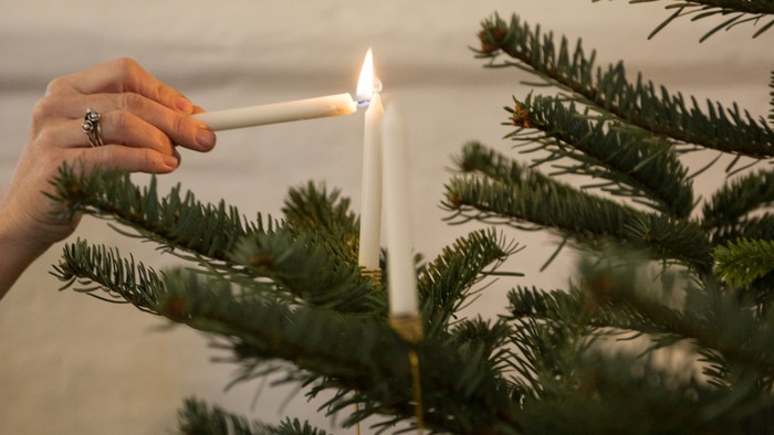 En hånd tænder en lys på en juletree