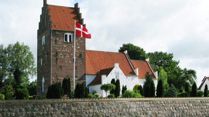 En dansk kirke med flag og murstengevær.