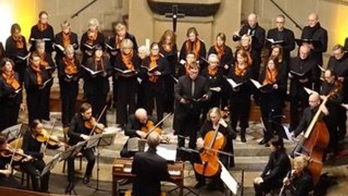 Ein großer Chor und ein Orchester treten gemeinsam in einem prächtigen Konzertsaal auf.