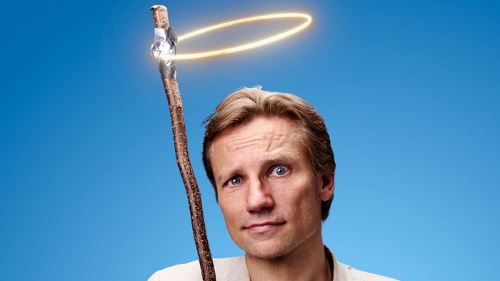 En person i en lys jakke holder en glødende stav med et glorielignende lys over hovedet.