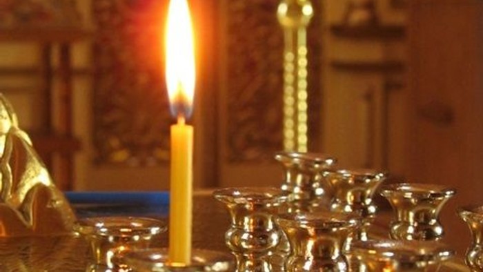 Eine brennende Kerze steht auf einem Tisch mit mehreren Kerzenhaltern