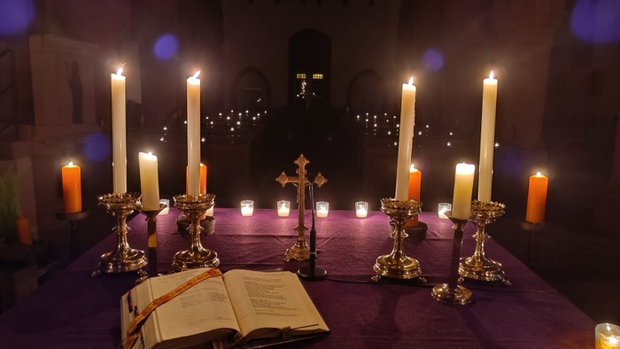 Kirchenaltar mit brennenden Kerzen und aufgeschlagenem Buch
