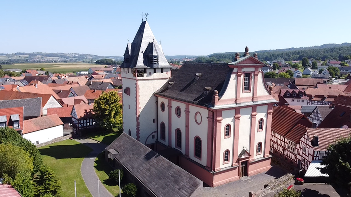 Luftaufnahme einer Stadt mit einer markanten Kirche und umliegenden Häusern.