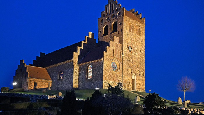 En stor kirke med tårn og klokker, belyset om natten