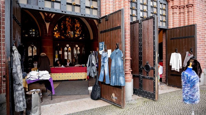 Ein modischer Laden in einem historischen Gebäude mit alten Türen und einer Frau, die Kleidung betrachtet
