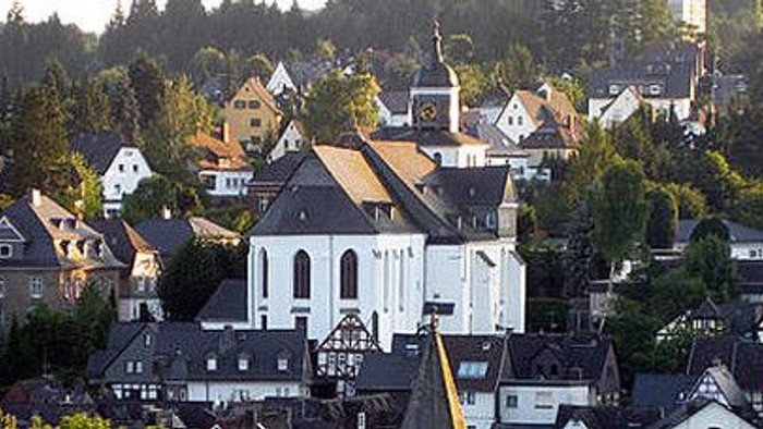 Ein malerisches Dorf mit einer großen Kirche im Zentrum, umgeben von vielen Häusern und Bäumen.
