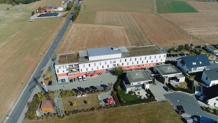 Ein großes Gebäude mit Parkplatz und umliegender Landwirtschaftsfläche