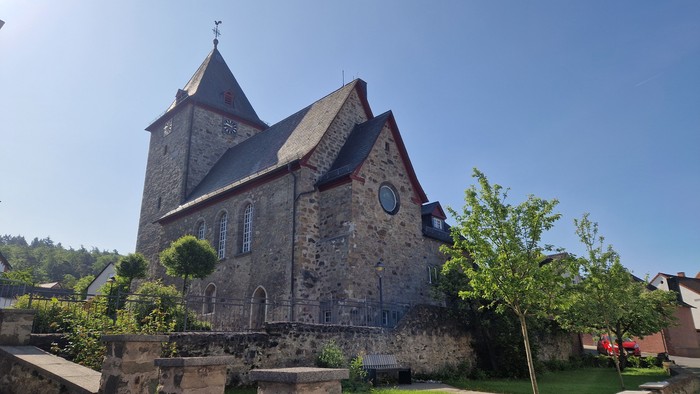 Altes steinernes Kirchgebäude mit spitzen Dach unter klarem Himmel
