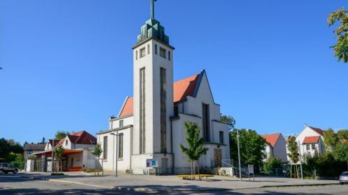 Kirchengebäude mit hohem Turm und rotem Dach in ruhiger Umgebung