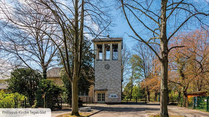 Ein hoher Turm steht in einem Park mit Bäumen und Büschen.