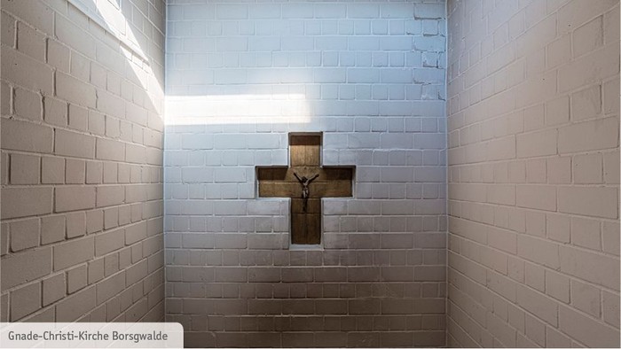 Ein Kreuz an einer Ziegelwand in einem kleinen Raum