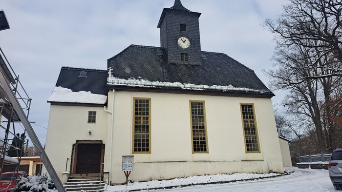 Weißes Kirchengebäude mit Uhrturm und Schnee