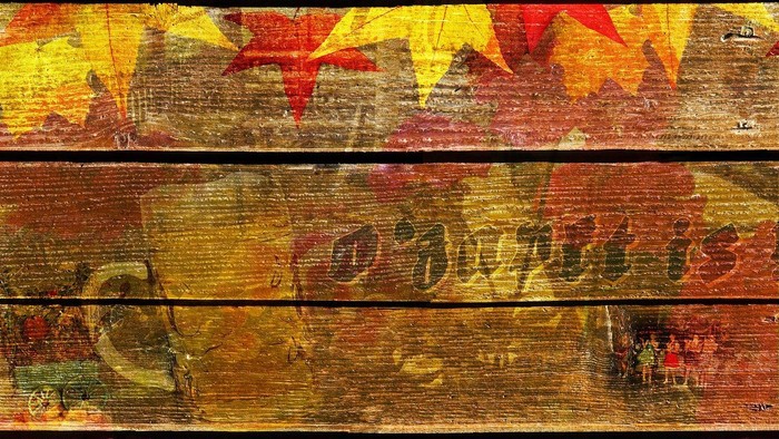 Bunte Herbstblätter auf Holzbalken, darauf ein Bierkrug mit Text daneben
