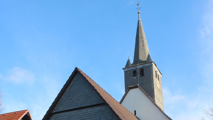 Außenansicht der evangelischen Kirche in Viesebeck. Weiß verputztes Kirchenschiff mit dunklem Dach und Turm mit schieferverkleideter Spitze.
