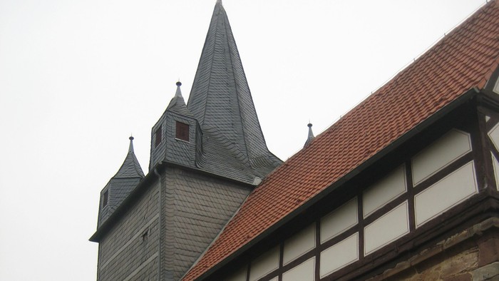 Außenansicht der evangelischen Kirche in Oelshausen. Natursteingebäude mit Fachwerkzone und rotem Ziegeldach.