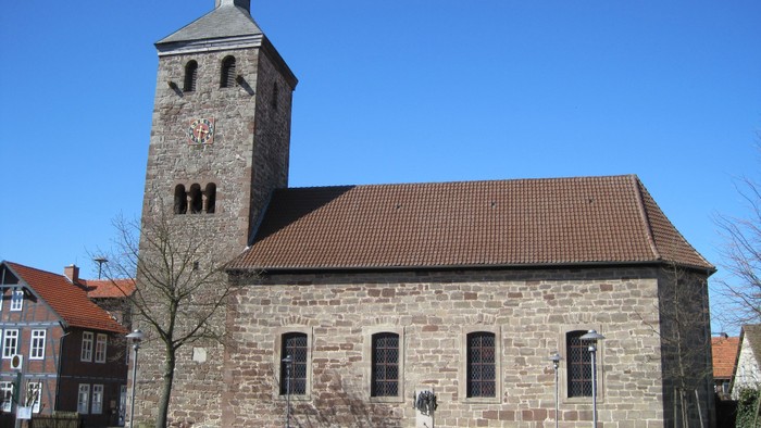 Außenansicht der evangelischen Kirche in Istha. Natursteingebäude mit braunem Ziegeldach und hohem Turm mit schiefergedeckter Haube.