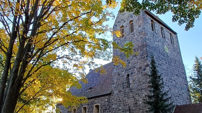 Dorfkirche Marienfelde umgeben von Bäumen mit Herbstlaub