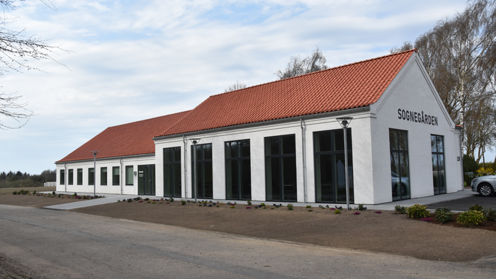 Et hvidt bygning med rødt tag og store vinduer.