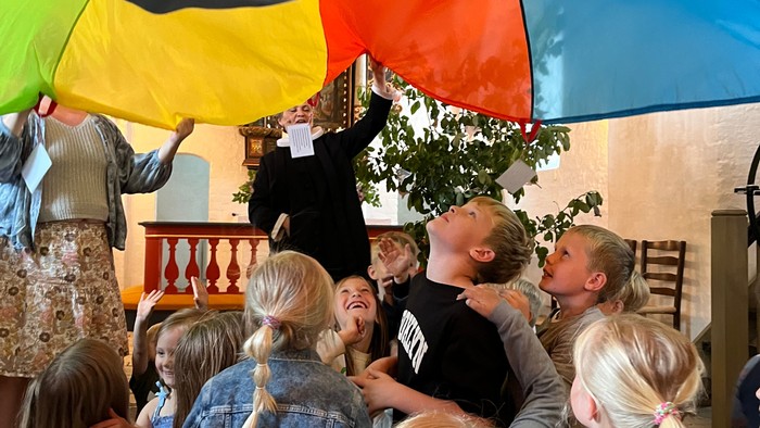 En gruppe børn under en regnbuet paraply
