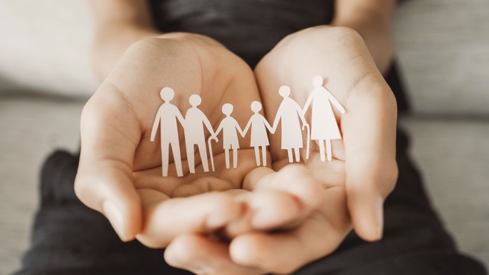 Eine Person hält eine Pappfamilie in den Händen