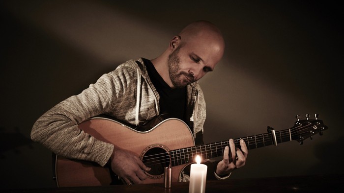 Ein Mann spielt Gitarre bei Kerzenschein.